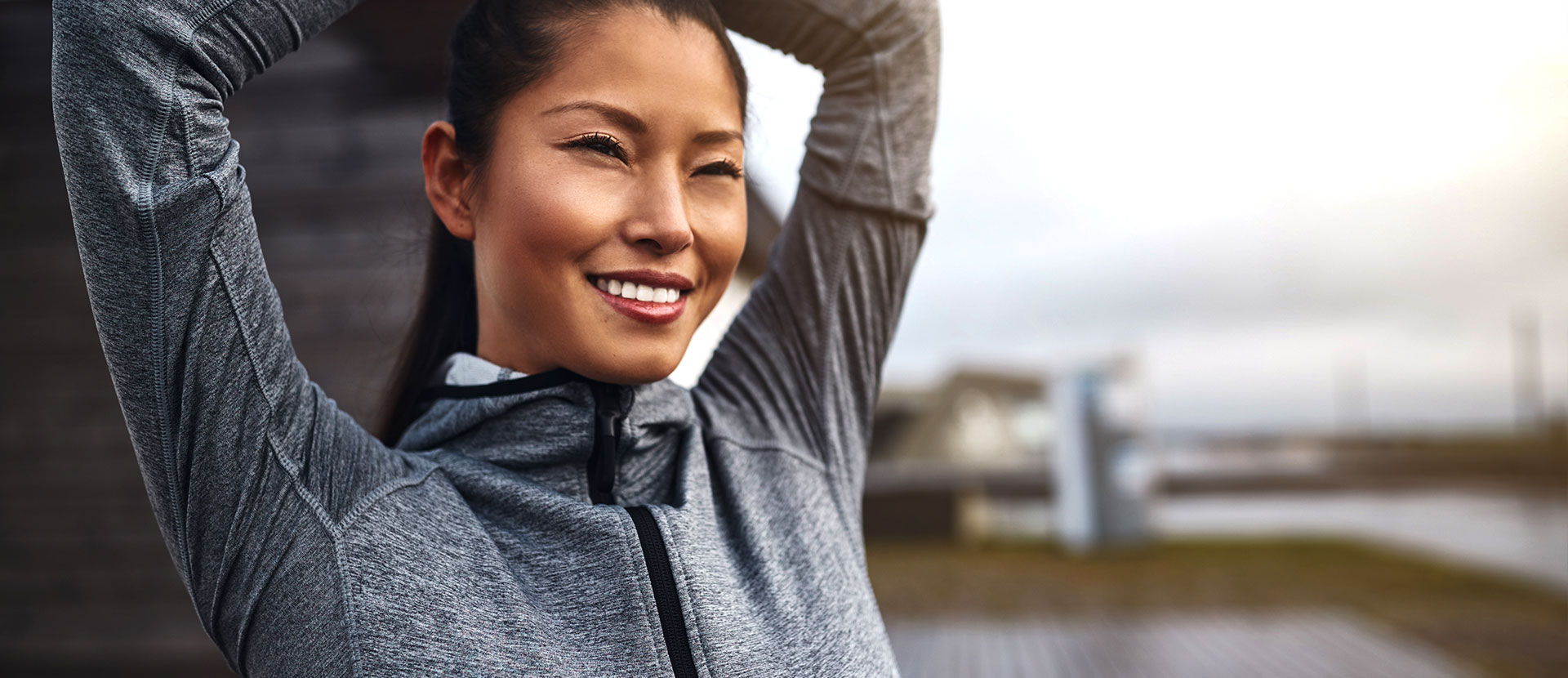 Asian woman smiling wearing gray jacket getting ready for ride