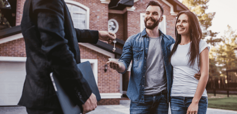 two people standing in front of a house with a sales agent