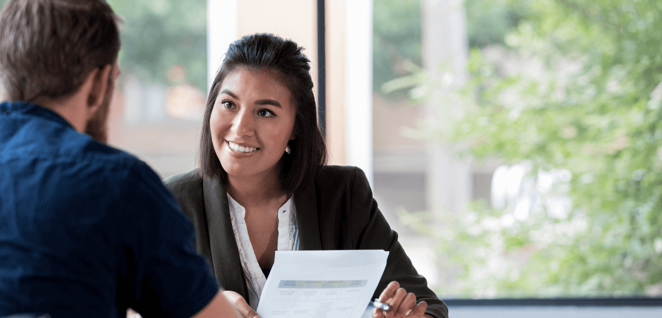 Female employee sitting talking to male customer