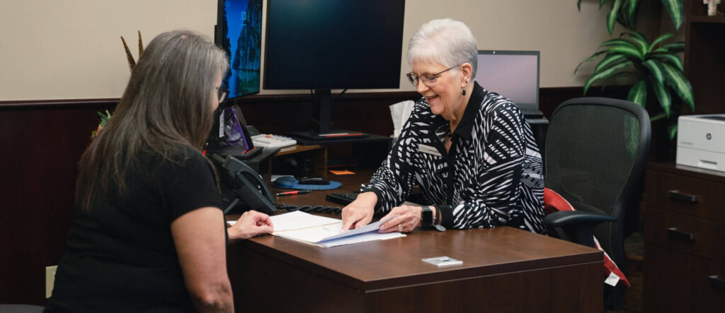Two women discussing paperwork at a desk in an office