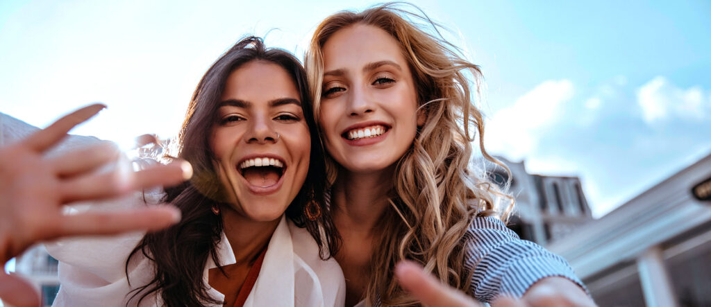 Two smiling young women taking a selfie outdoors