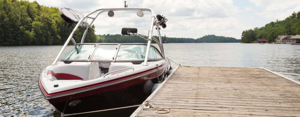 Motorboat tied to a wooden dock on a calm lake surrounded by trees