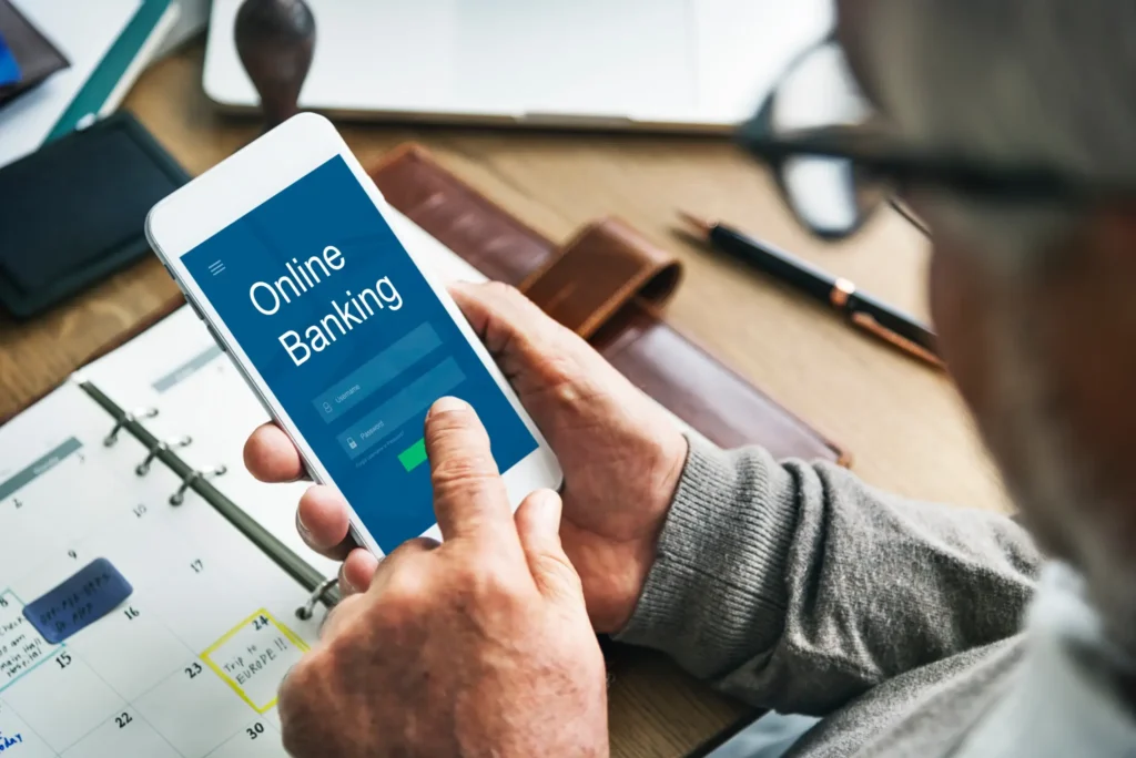 Person using a smartphone displaying Online Banking at a desk