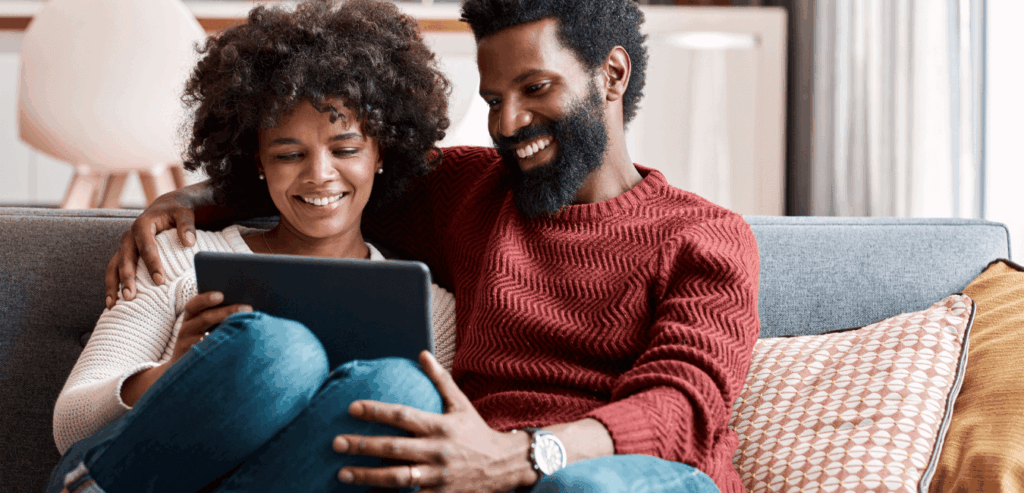 Smiling couple sitting on a couch and looking at a tablet together