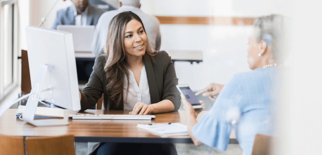 Bank employee speaking with a senior woman at a desk