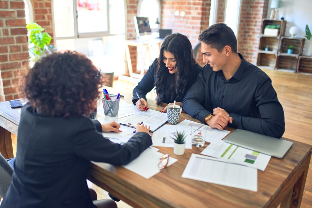 Couple reviewing loan paperwork with a financial adviser at a desk